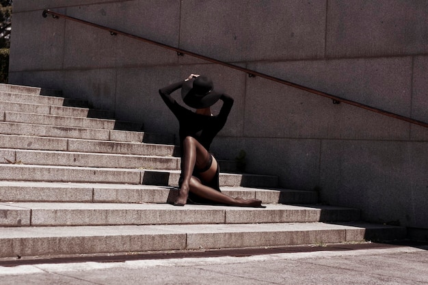 Full length of young woman wearing hat sitting on steps