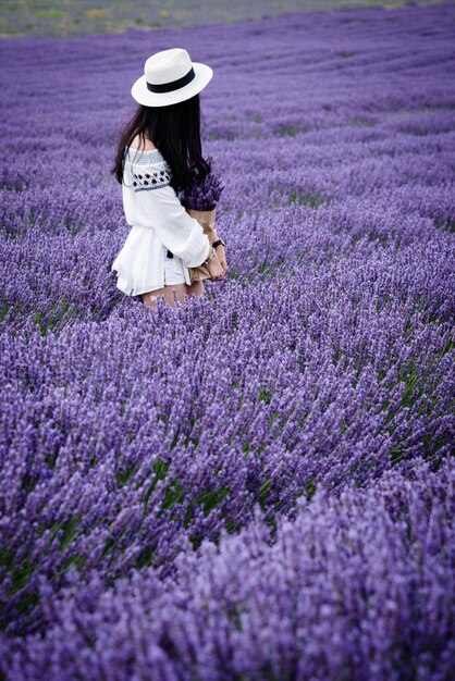 Foto lunghezza piena di giovane donna con fiori sul campo