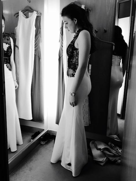 Foto full length zijbeeld van een vrouw die een nieuwe jurk probeert in de kleedkamer