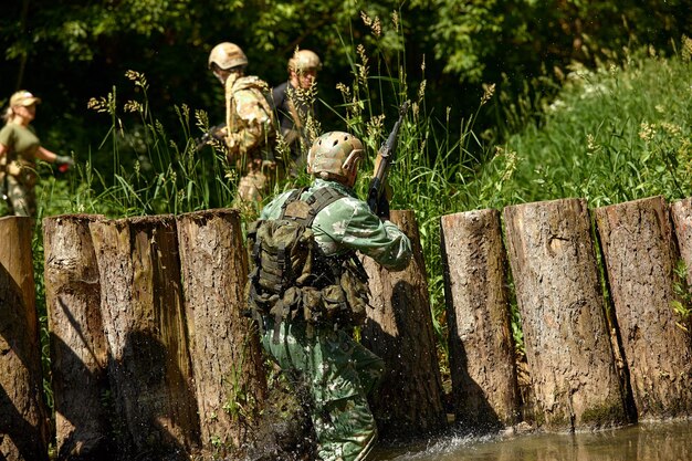 Full military experience One day commando running through the water with automatic rifle replica