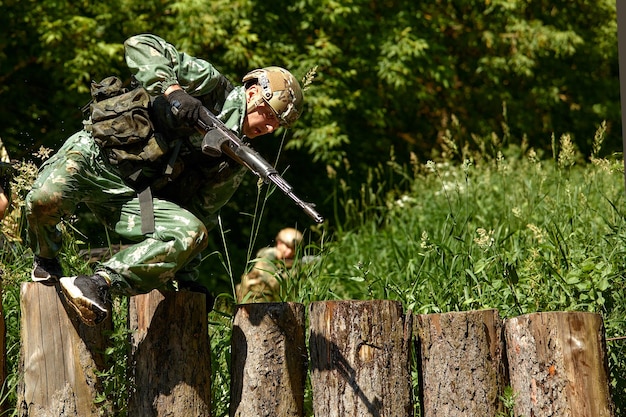 Photo full military experience one day commando running through the water with automatic rifle replica