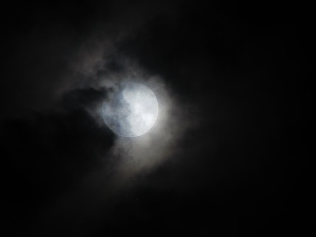 A full moon is visible through the clouds in the night sky.