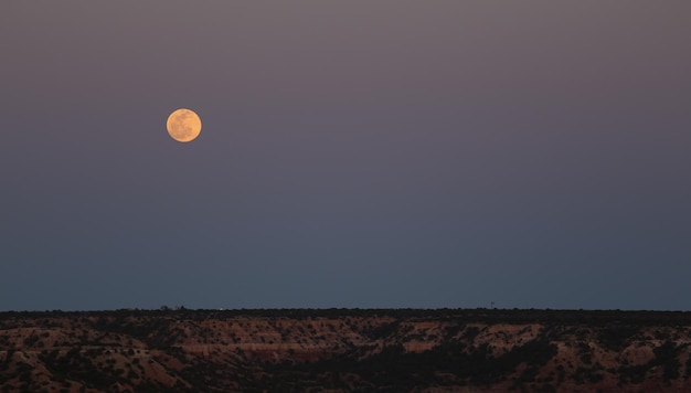 Full moon over landscape at dusk