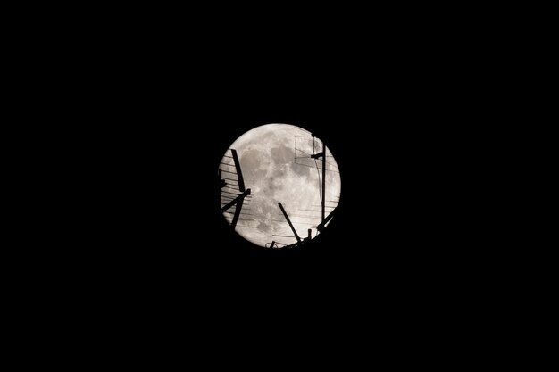 Photo full moon at night the moon passes behind the television antenna in the foreground