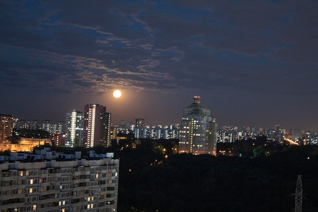 A full moon in the night sky of the metropolis against the background of sleeping houses