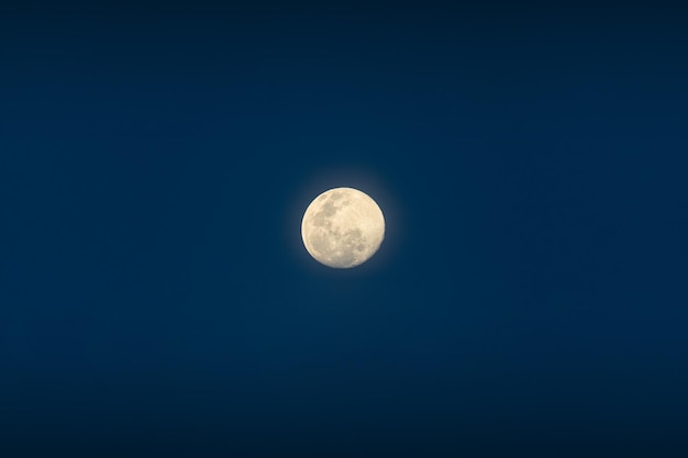 Полная луна сияет на голубом небе в сумерках