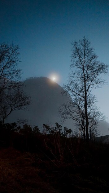 a full moon shines over a mountain