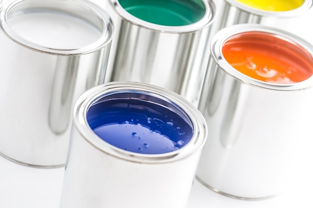 Full of multicolored paint cans on white table.