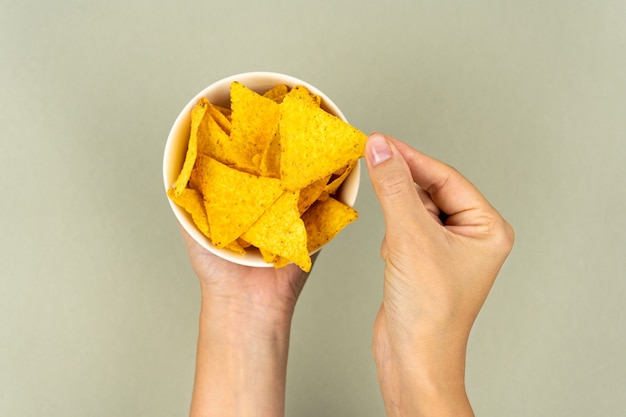 A full plate of crunchy nachos corn triangles in women's hands.