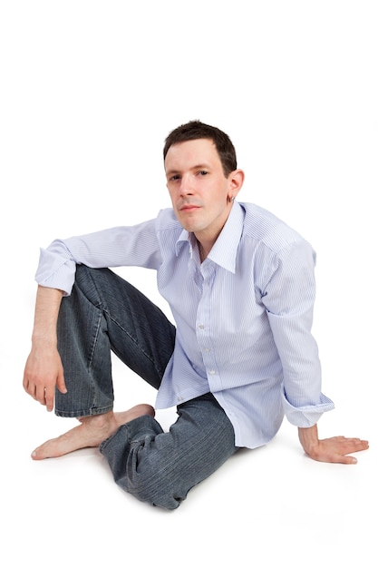 잘생긴 남자의 전체 초상화는 흰색 배경에 고립 된 바닥에 앉아 있다