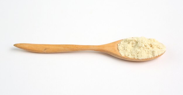 Full Powdered milk in wooden spoon over white 