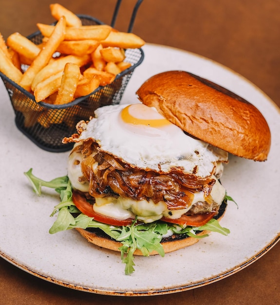 Foto burger di manzo rustico con patatine fritte e uova fritte