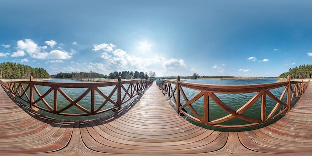 Panorama sferico hdri completo senza soluzione di continuità vista a 360 gradi sul ponte pedonale in legno dell'ampio lago in una giornata di sole panorama a 360 gradi in proiezione equirettangolare contenuto di realtà virtuale vr ar pronto