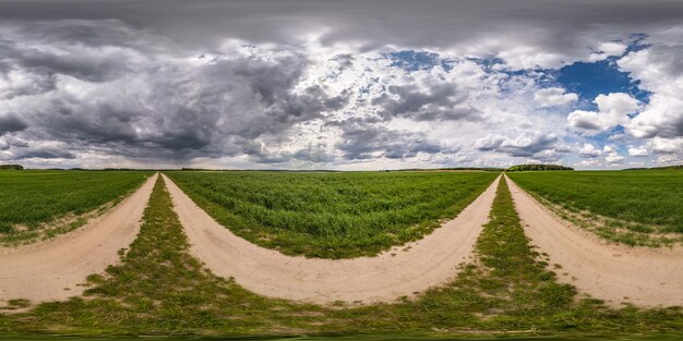 Фото Полная бесшовная сферическая панорама hdri с углом обзора 360 градусов на бездорожной гравийной дороге среди полей с пасмурным небом перед бурей в равнопрямоугольной проекции, готовой для контента виртуальной реальности vr ar