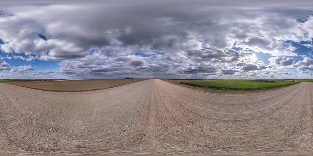 Full seamless spherical hdri panorama 360 degrees angle view on gravel road among fields in spring day with storm clouds before rain in equirectangular projection ready for VR AR content