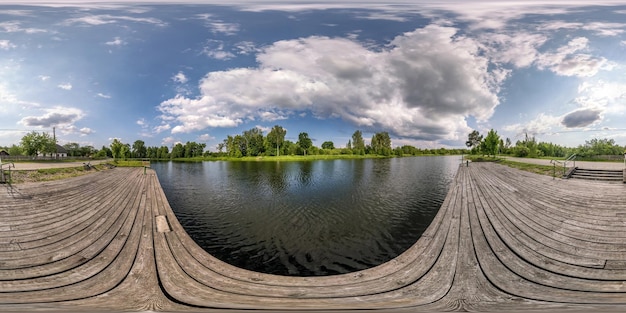 Full seamless spherical hdri panorama 360 degrees angle view on wooden pier of lake or rivere with beautiful clouds in equirectangular projection VR content