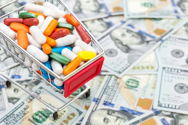 Full shopping cart with pills on background of dollar bills Close up Space for text