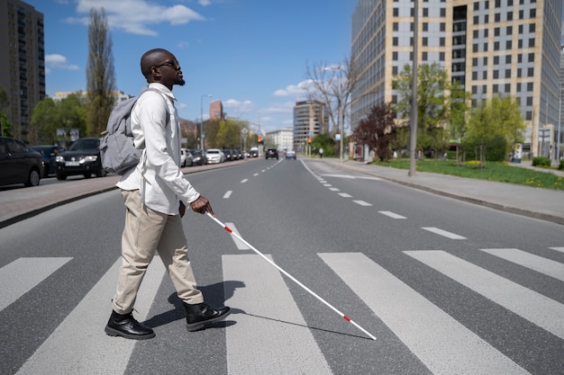 写真 通りを横断するフルショットの盲目の男