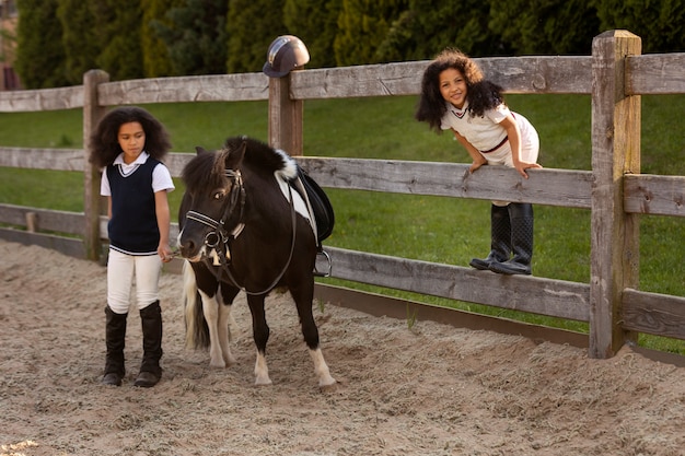 Photo full shot children learning to ride horses