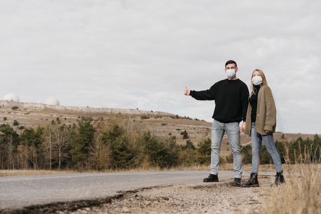 Full shot couple hitchhiking