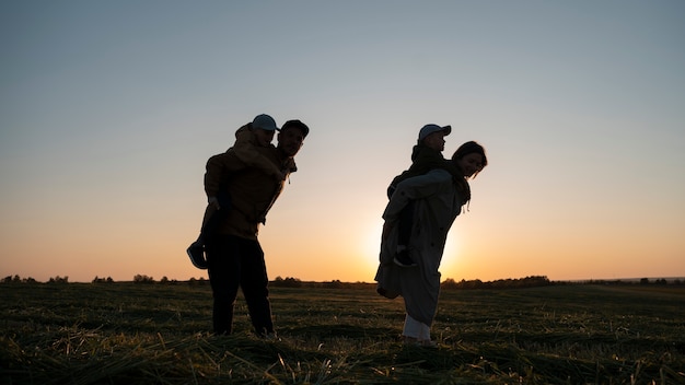 Foto siluetta della famiglia del colpo pieno che si diverte al tramonto