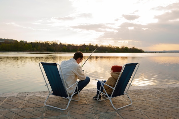 Full shot father and son hanging out on a jetty