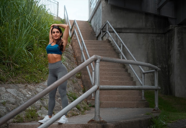 Full shot fit woman stretching outdoors