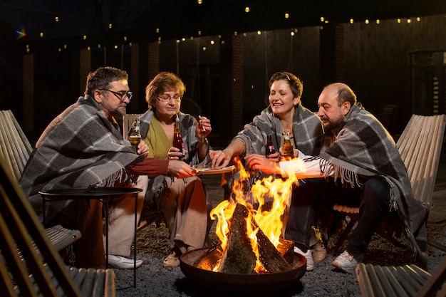 Photo full shot friends sitting around fire