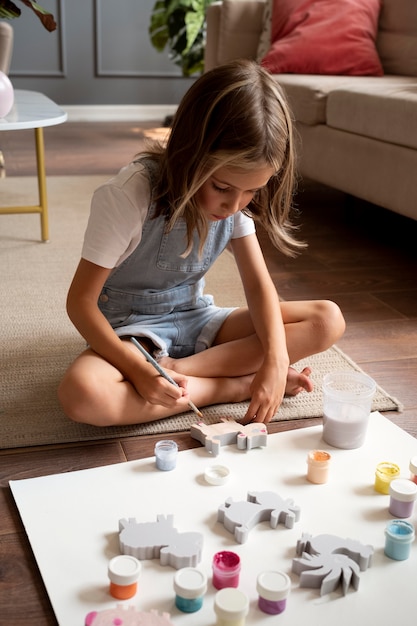 Full shot girl on floor painting