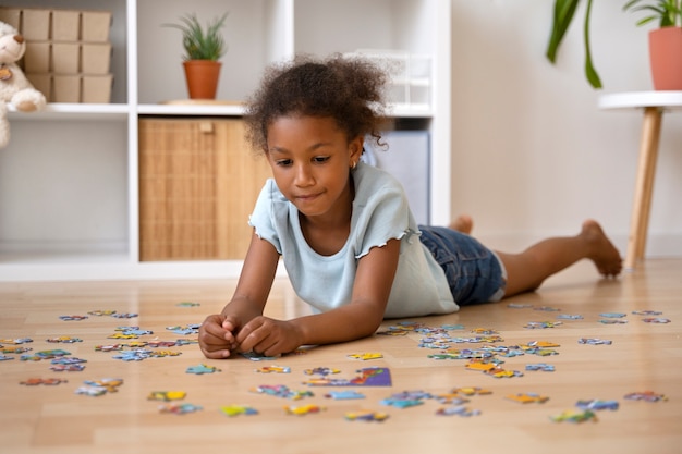 Foto ragazza del colpo pieno che fa puzzle sul pavimento