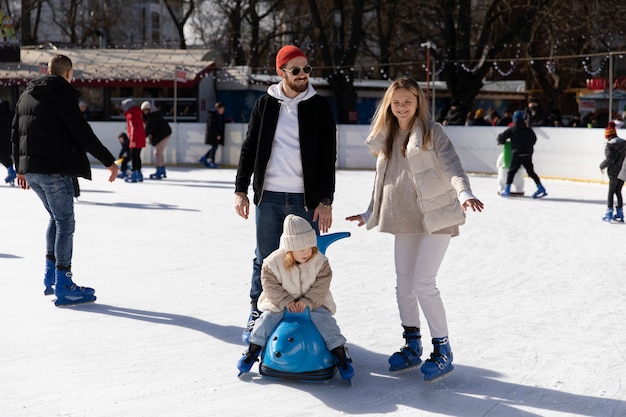 Foto famiglia felice a tutto campo che si diverte alla pista di pattinaggio