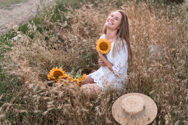 Full shot happy woman holding sunflower