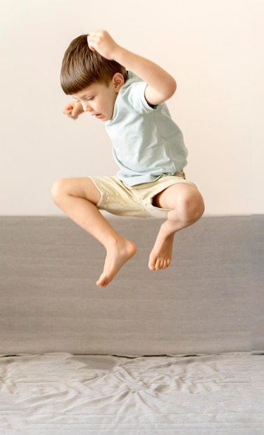 Photo full shot kid jumping on couch