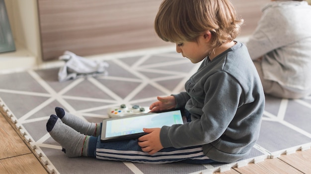 Foto bambino a tutto campo con tablet al chiuso