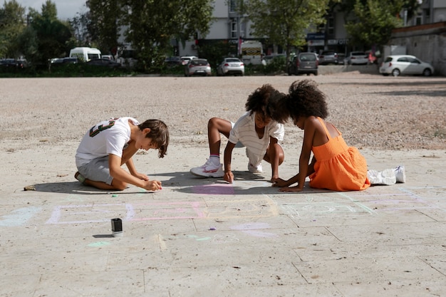 写真 舗装に絵を描くフルショットの子供たち