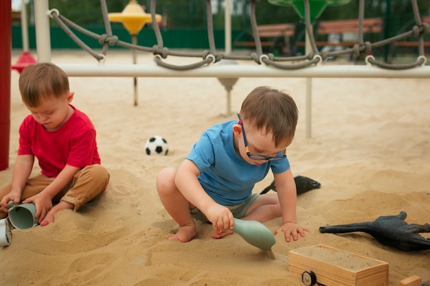 写真 砂で遊ぶフルショットの子供たち