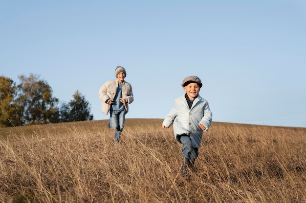 写真 フィールドで走っているフルショットの子供たち