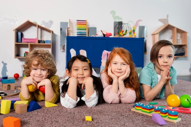 写真 幼稚園で一緒に座っているフルショットの子供たち