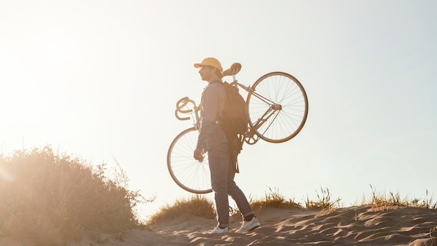 自転車を運ぶフルショットの男