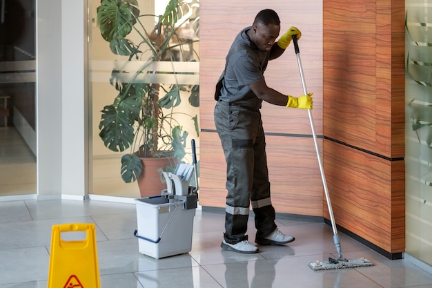 Photo full shot man cleaning office floor