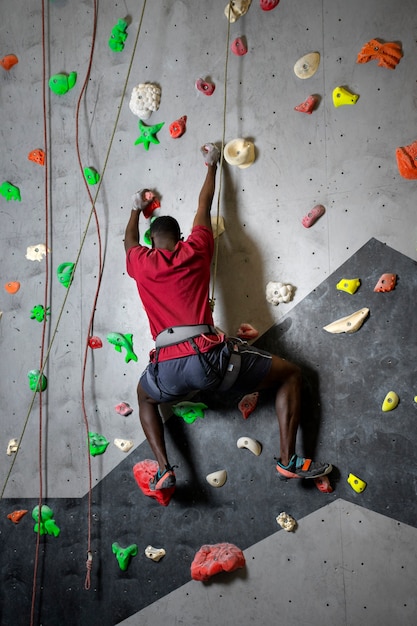 Full shot man climbing wall