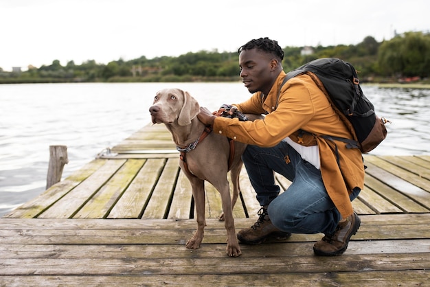 Foto uomo a tutto campo e cane carino vicino al lago