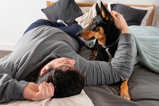 Foto uomo e cane del colpo pieno a letto