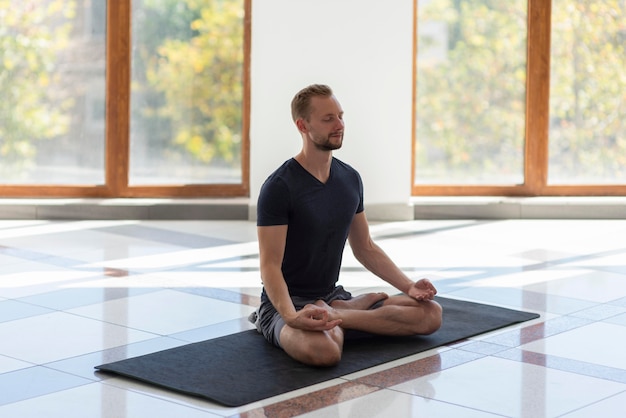 Foto uomo pieno del colpo che fa yoga sulla stuoia