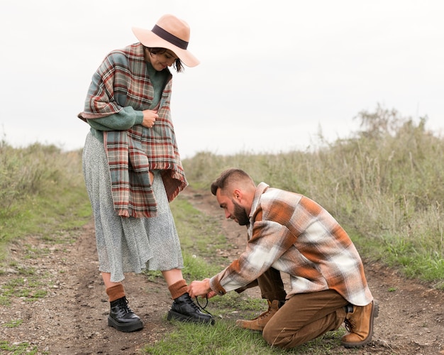 Photo full shot man tying girlfriend's shoelaces