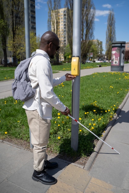 Foto uomo del colpo pieno che utilizza il dispositivo di attraversamento della strada