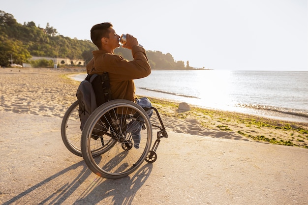 Full shot man in wheelchair drinking