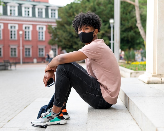 Photo full shot man with mask sitting on stairs