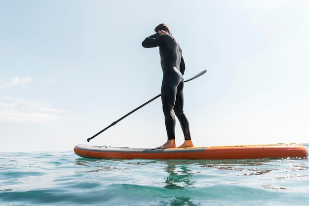 Photo full shot man with suit on surfboard