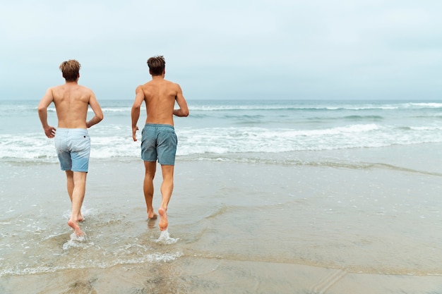 Full shot men running on beach